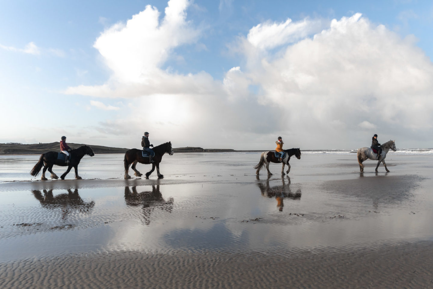 people riding horses on beach